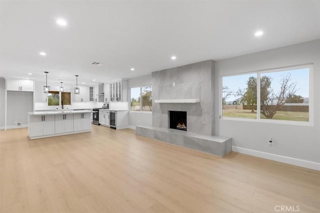 unfurnished living room featuring beverage cooler, a fireplace, sink, and light wood-type flooring