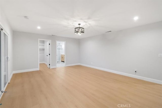 unfurnished room featuring an inviting chandelier and light hardwood / wood-style flooring