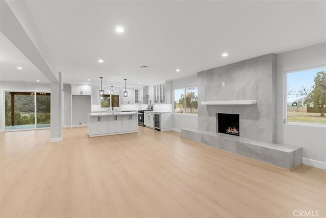 unfurnished living room with beverage cooler, a fireplace, and light hardwood / wood-style floors