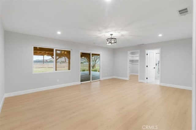 unfurnished room with a notable chandelier and light wood-type flooring