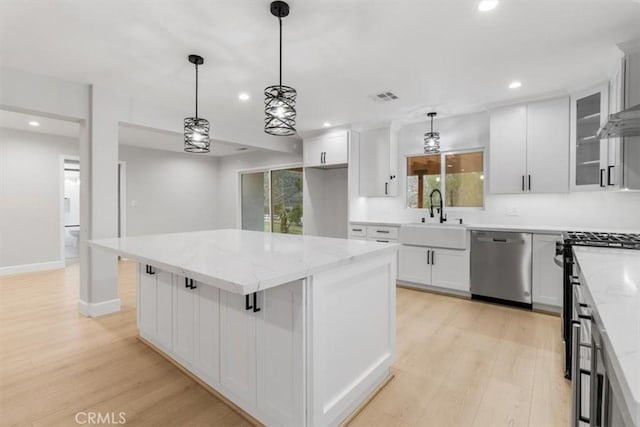 kitchen with sink, a center island, appliances with stainless steel finishes, pendant lighting, and white cabinets