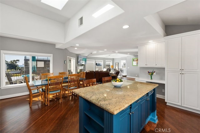 kitchen with blue cabinetry, a skylight, a center island, dark hardwood / wood-style floors, and white cabinets