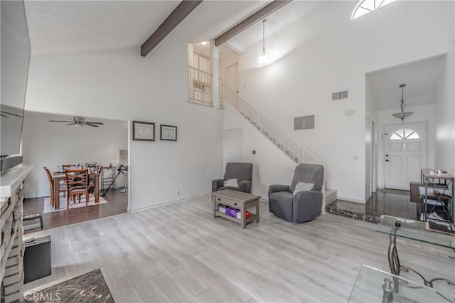 living room featuring visible vents, beamed ceiling, stairs, and wood finished floors