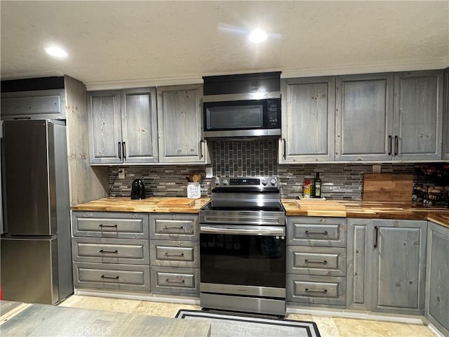 kitchen with tasteful backsplash, gray cabinets, appliances with stainless steel finishes, and wood counters