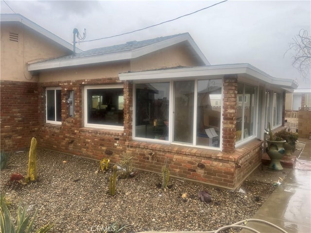 view of side of property with brick siding and a sunroom