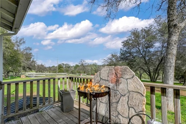 wooden deck with an outdoor fire pit and a lawn