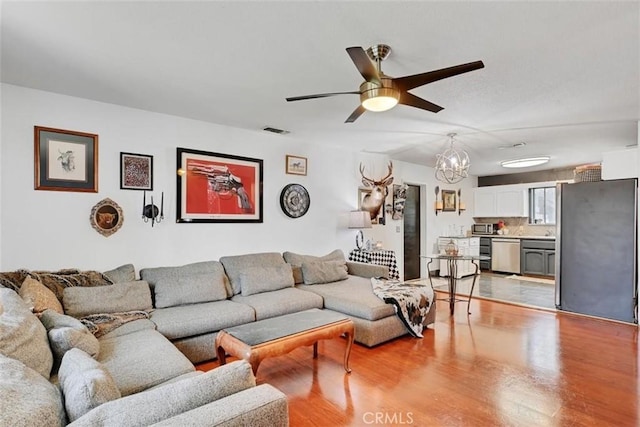 living room featuring ceiling fan with notable chandelier and light wood-type flooring