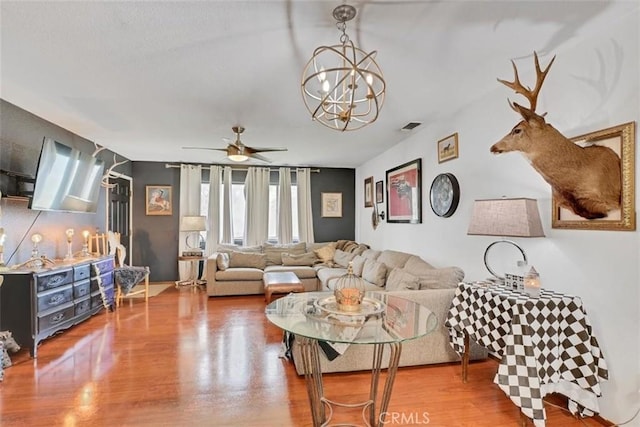 living room featuring ceiling fan with notable chandelier and wood-type flooring