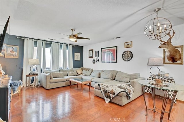 living room with ceiling fan with notable chandelier and wood-type flooring