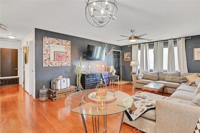 living room with light wood-type flooring and ceiling fan with notable chandelier