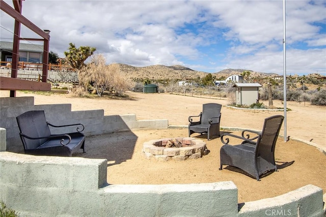 view of patio featuring a mountain view, a storage unit, and a fire pit