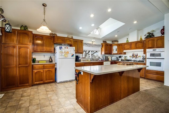 kitchen with a center island, a kitchen breakfast bar, pendant lighting, white appliances, and vaulted ceiling with skylight