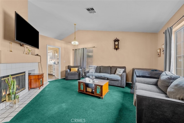 living room featuring a tiled fireplace, lofted ceiling, and carpet flooring