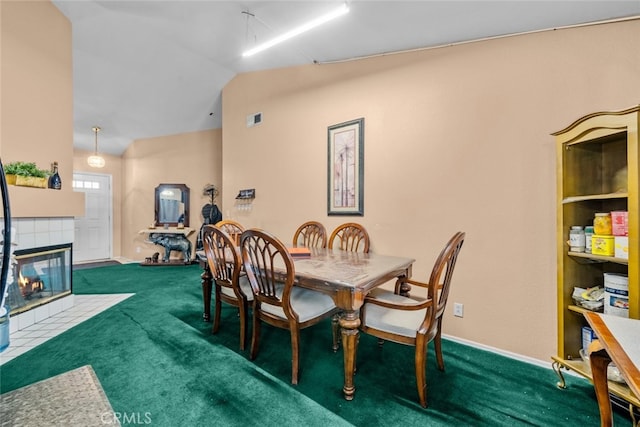 carpeted dining space featuring a tile fireplace and vaulted ceiling