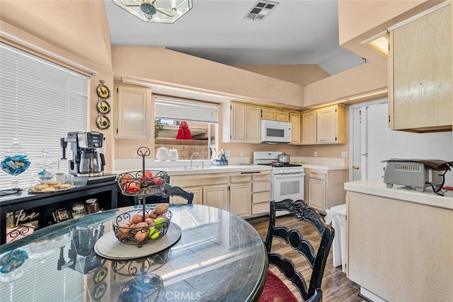 kitchen with vaulted ceiling, sink, light brown cabinetry, and white appliances