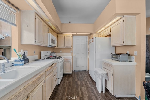 kitchen with dark wood-type flooring, white appliances, tile counters, and sink