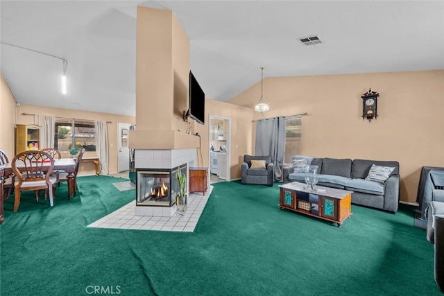 carpeted living room featuring a tiled fireplace and vaulted ceiling