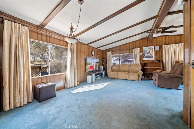 living room featuring carpet floors, lofted ceiling with beams, a healthy amount of sunlight, and wood walls