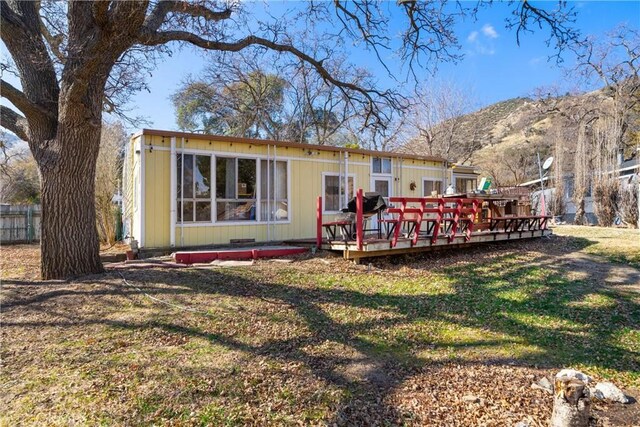 rear view of house with a lawn and a deck with mountain view