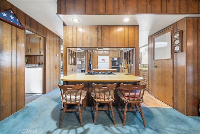 dining room with washer / clothes dryer, wooden walls, and light wood-type flooring