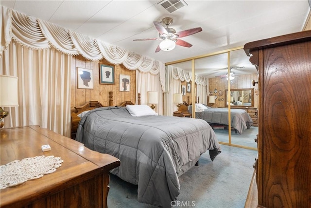 carpeted bedroom with wooden walls, a closet, and ceiling fan