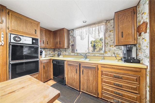 kitchen with black dishwasher, sink, and double oven