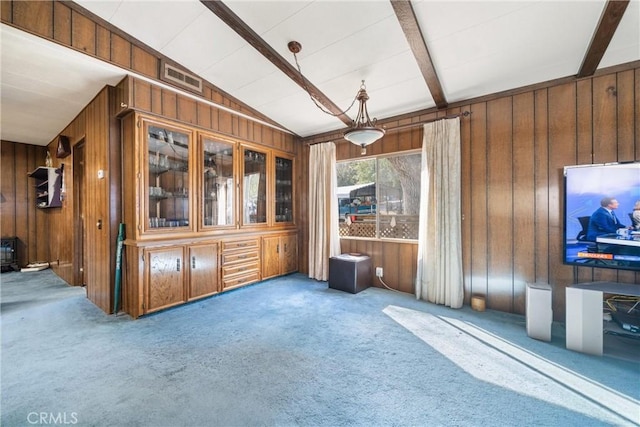 unfurnished living room with vaulted ceiling with beams, wooden walls, and carpet flooring