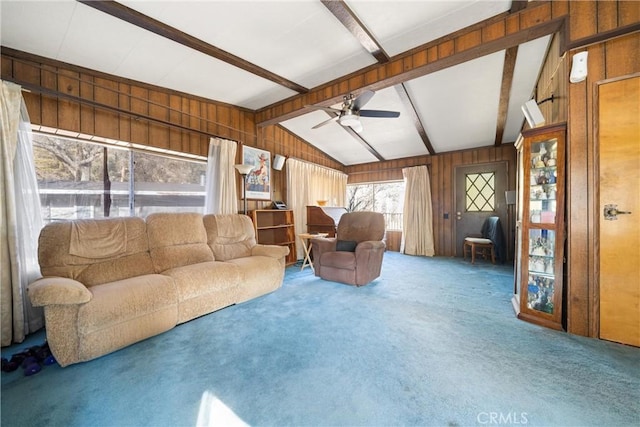 carpeted living room featuring ceiling fan, vaulted ceiling with beams, and wooden walls