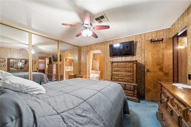 bedroom featuring light colored carpet, a closet, ceiling fan, and ensuite bathroom