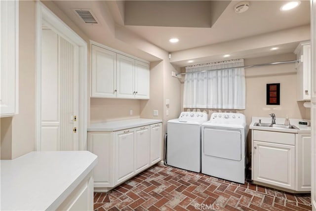 laundry area with washing machine and dryer, cabinets, and sink