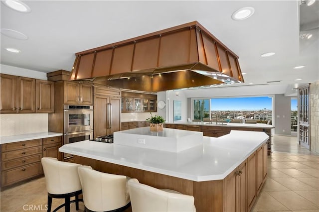 kitchen with appliances with stainless steel finishes, a breakfast bar area, a spacious island, and light tile patterned floors