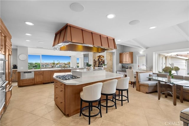 kitchen featuring a kitchen bar, light tile patterned floors, a kitchen island, and appliances with stainless steel finishes