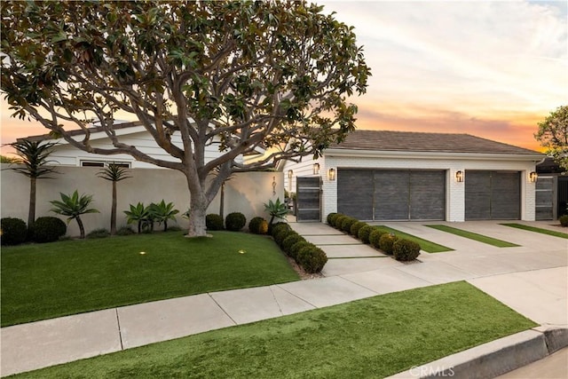 view of front of property with a garage and a lawn