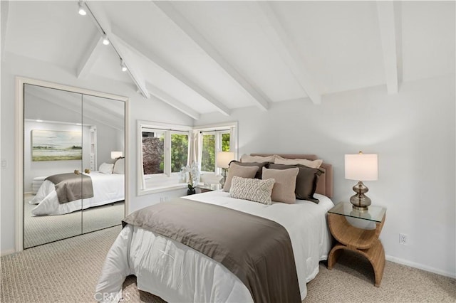 bedroom featuring a closet, rail lighting, vaulted ceiling with beams, and light colored carpet