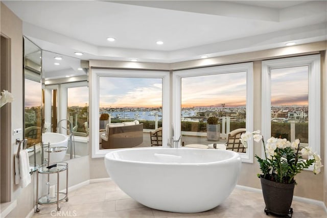 bathroom featuring a wealth of natural light, tile patterned flooring, and a bath