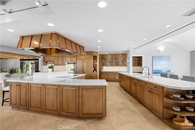 kitchen with a large island, black electric cooktop, sink, oven, and a kitchen bar