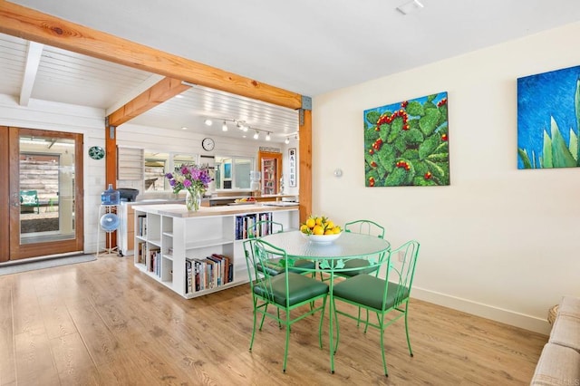 dining area with beam ceiling, light hardwood / wood-style flooring, and rail lighting