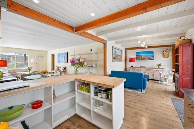 interior space with beamed ceiling, wood walls, butcher block countertops, and light wood-type flooring