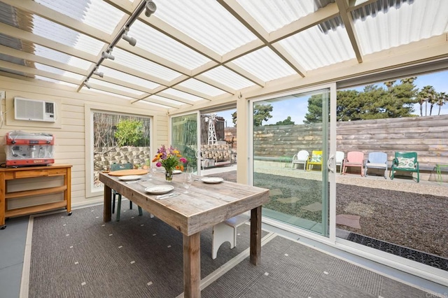 sunroom / solarium featuring track lighting, plenty of natural light, and a wall mounted AC