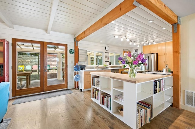 interior space featuring sink, light hardwood / wood-style flooring, stainless steel refrigerator, beam ceiling, and french doors