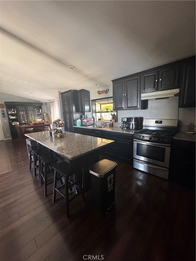 8734 Nevada Rd, Phelan, CA 92371 - kitchen with stainless steel range with gas stovetop, dark wood finished floors, under cabinet range hood, light stone countertops, and a breakfast bar area