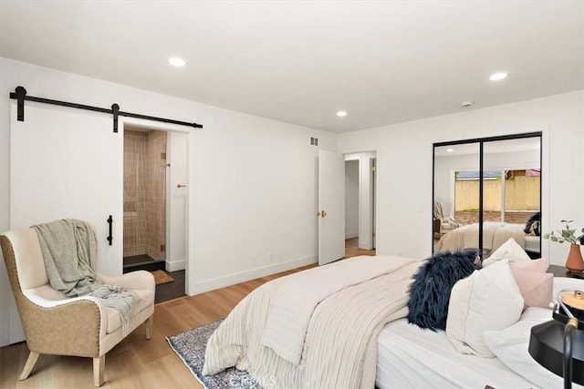 bedroom featuring a closet, a barn door, and light hardwood / wood-style flooring