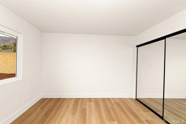 unfurnished bedroom featuring a closet and light wood-type flooring