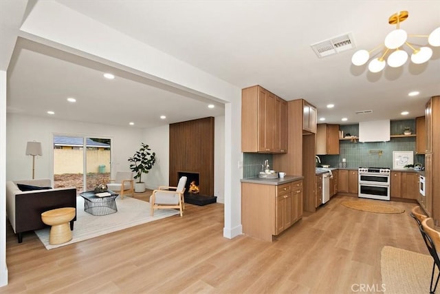 kitchen with double oven range, a large fireplace, light hardwood / wood-style floors, and decorative backsplash