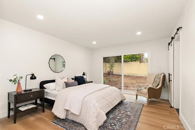 bedroom featuring a barn door, access to exterior, and light wood-type flooring