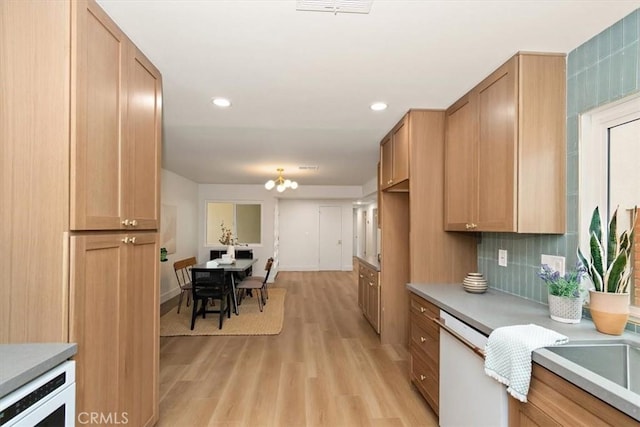 kitchen with dishwashing machine, wine cooler, a notable chandelier, tasteful backsplash, and light wood-type flooring