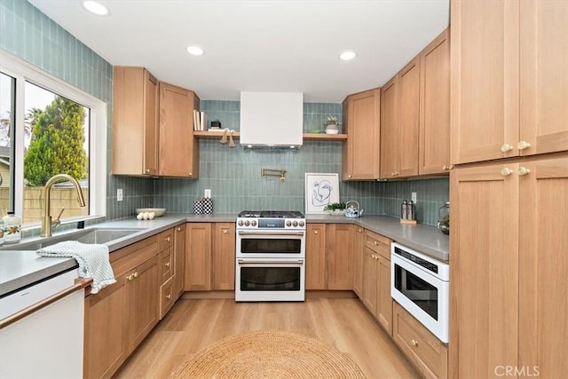 kitchen with built in microwave, sink, double oven range, light hardwood / wood-style floors, and wall chimney range hood