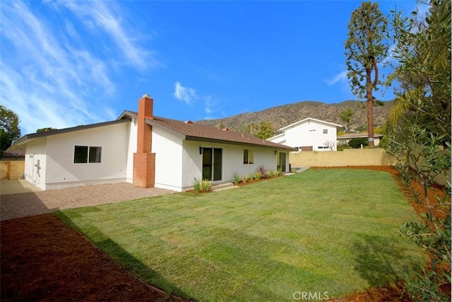 rear view of house with a mountain view and a lawn