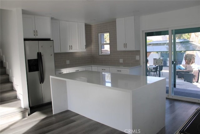 kitchen with a center island, stainless steel refrigerator with ice dispenser, light countertops, white cabinets, and a healthy amount of sunlight