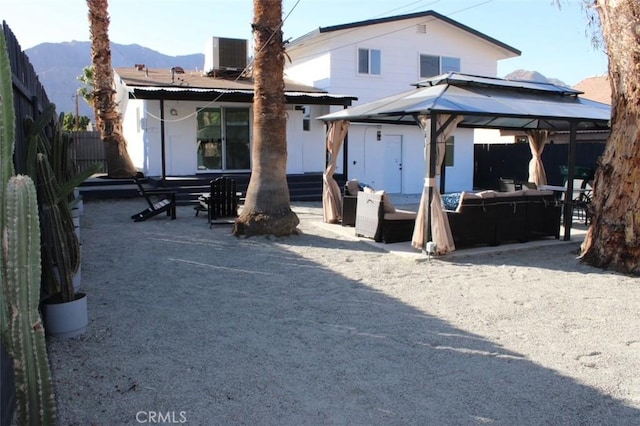 back of house featuring central air condition unit, outdoor lounge area, a gazebo, a mountain view, and fence